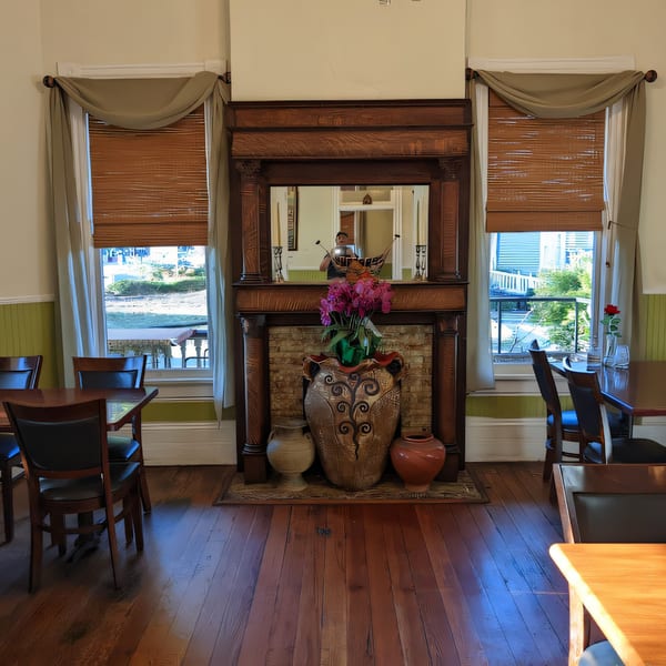 Interior of Thai Palace & Sushi Bar with a large wooden fireplace, mirror, and dining tables.