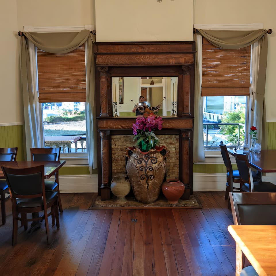 Interior of Thai Palace & Sushi Bar with a large wooden fireplace, mirror, and dining tables.