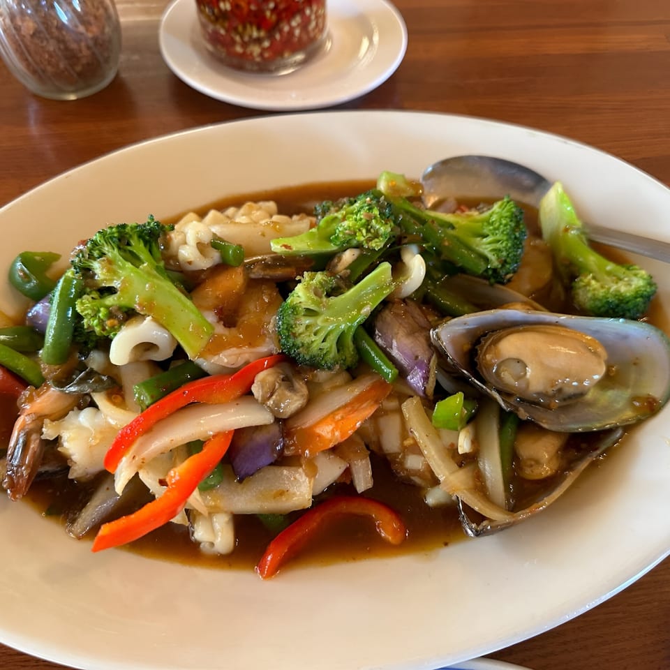 Thai seafood stir-fry with broccoli, bell peppers, and mussels in a rich brown sauce.