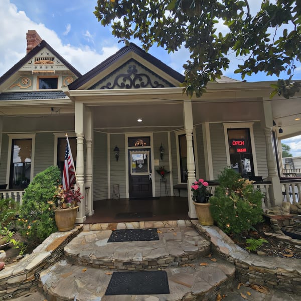 Exterior of Thai Palace & Sushi Bar, a light blue Victorian house with a porch and an "OPEN" sign.