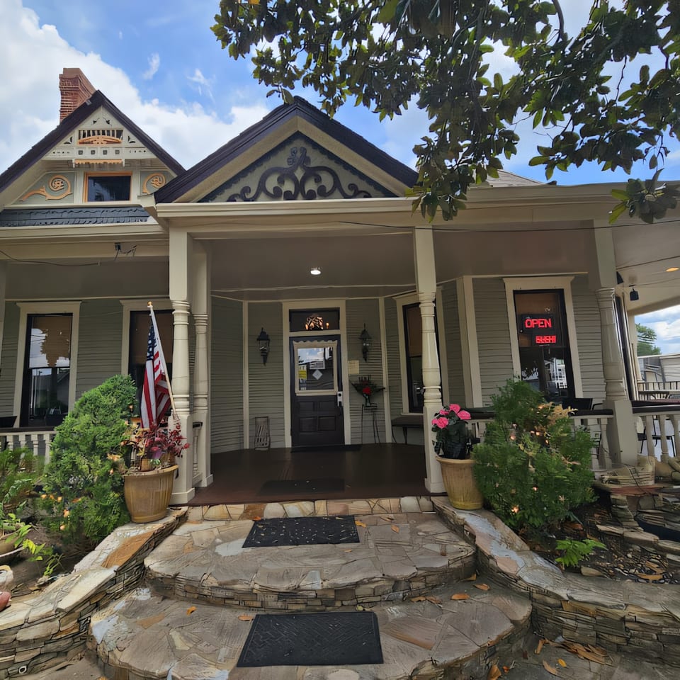 Exterior of Thai Palace & Sushi Bar, a light blue Victorian house with a porch and an "OPEN" sign.