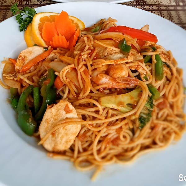Thai Palace & Sushi Bar's Pad See Ew with chicken, shrimp, and vegetables, garnished with orange and parsley.